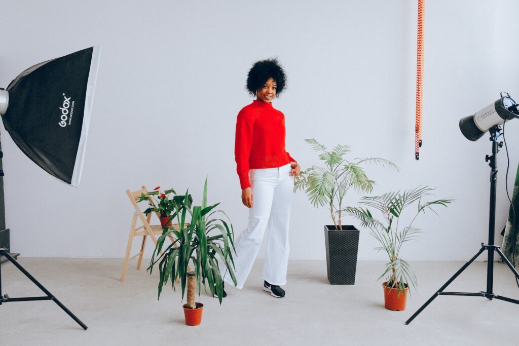 Smiling ethnic woman having photo session with plants