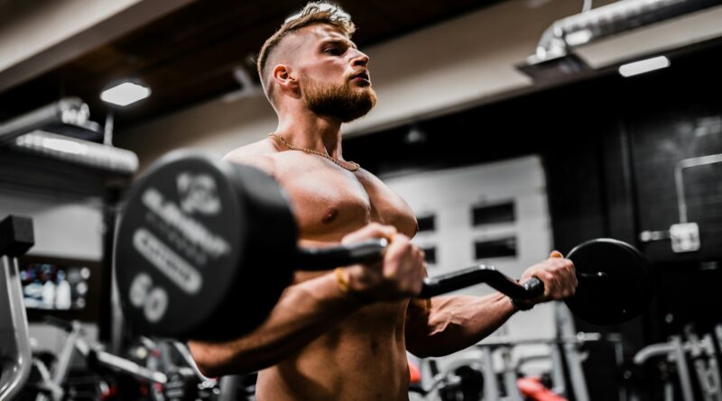 topless man in black shorts carrying black dumbbell